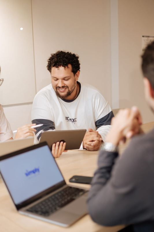 Aluno sorrindo durante uma aula, com notebook e tablet na mesa